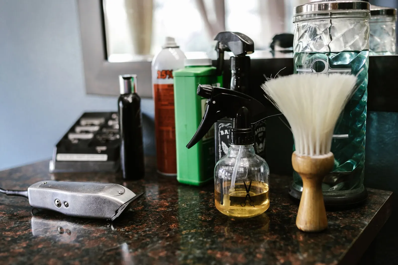 Outils de barbier posés sur le comptoir du salon : tondeuse, brosse et vaporisateur