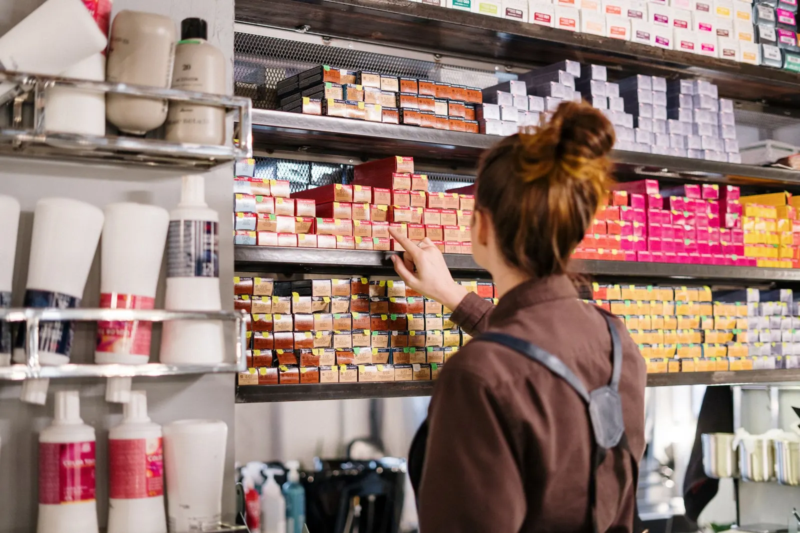 Coiffeuse rangeant des colorations aux teintes vives sur une étagère du salon