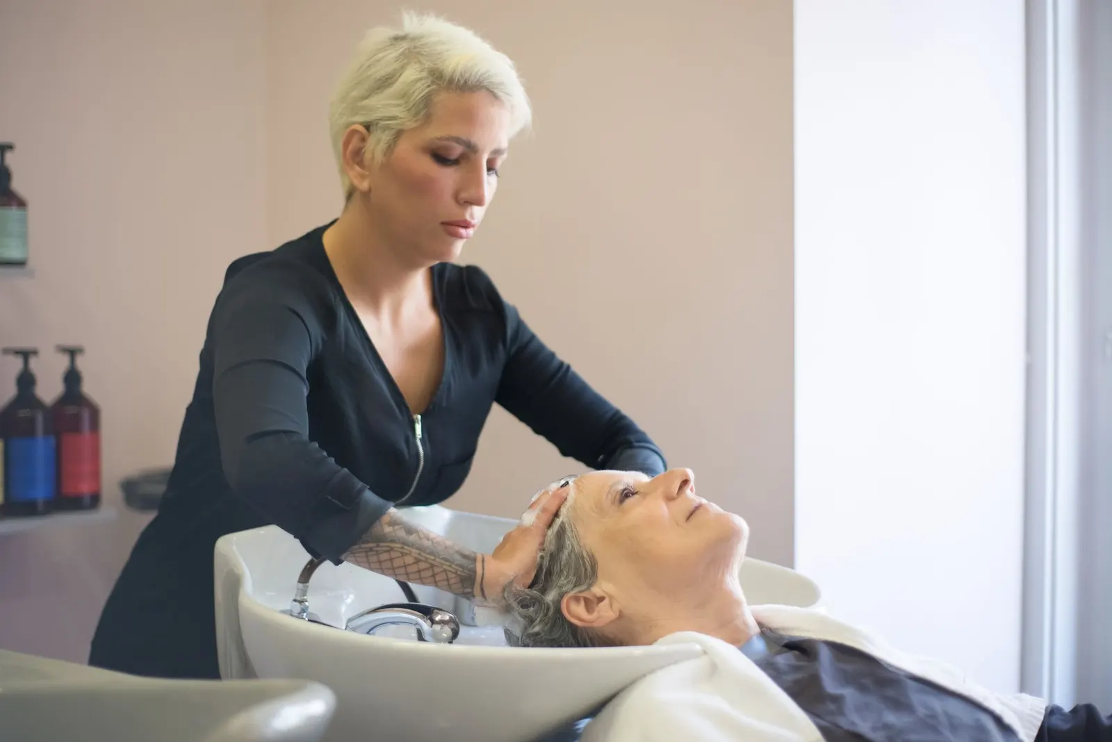 Coiffeuse offrant un shampoing détente à une cliente installée au bac